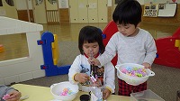 ひとつの容器に力を合わせて食べ物に見立てたフラワーブロックを入れている男の子と女の子