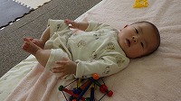 布団に寝ころんで両足を上げている男の子