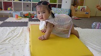 マットの上でハイハイする女の子