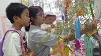 笹飾りをするお兄さんと女の子とお母さん