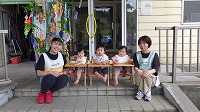 笹飾りの前で笑顔の先生と子どもたち