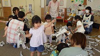 新聞紙の感触を楽しんでいる子ども達