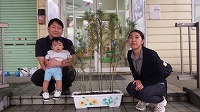 花の前でお父さんに抱っこされる男の子、隣にお母さん