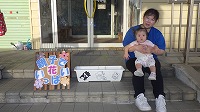 花の前でお母さんに抱っこされる女の子